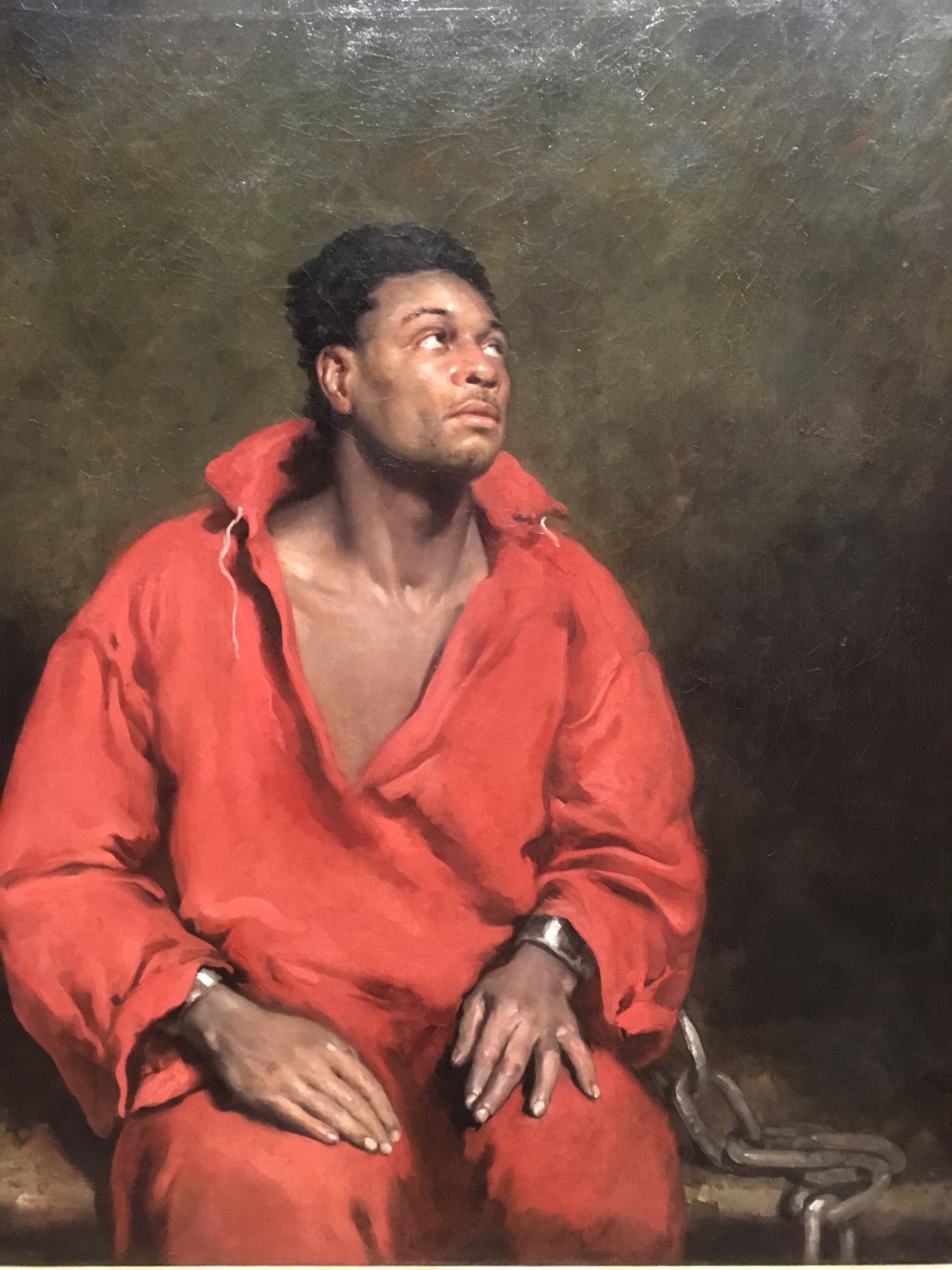 The captive slave:  A very powerful image.  Very sad expression. With almost a welling if tears in the eyes, the focus of the light informed us of his emotion. The detail in the hands is amazing—resigned.  Showing the body and dark surroundings gives us relevance. 