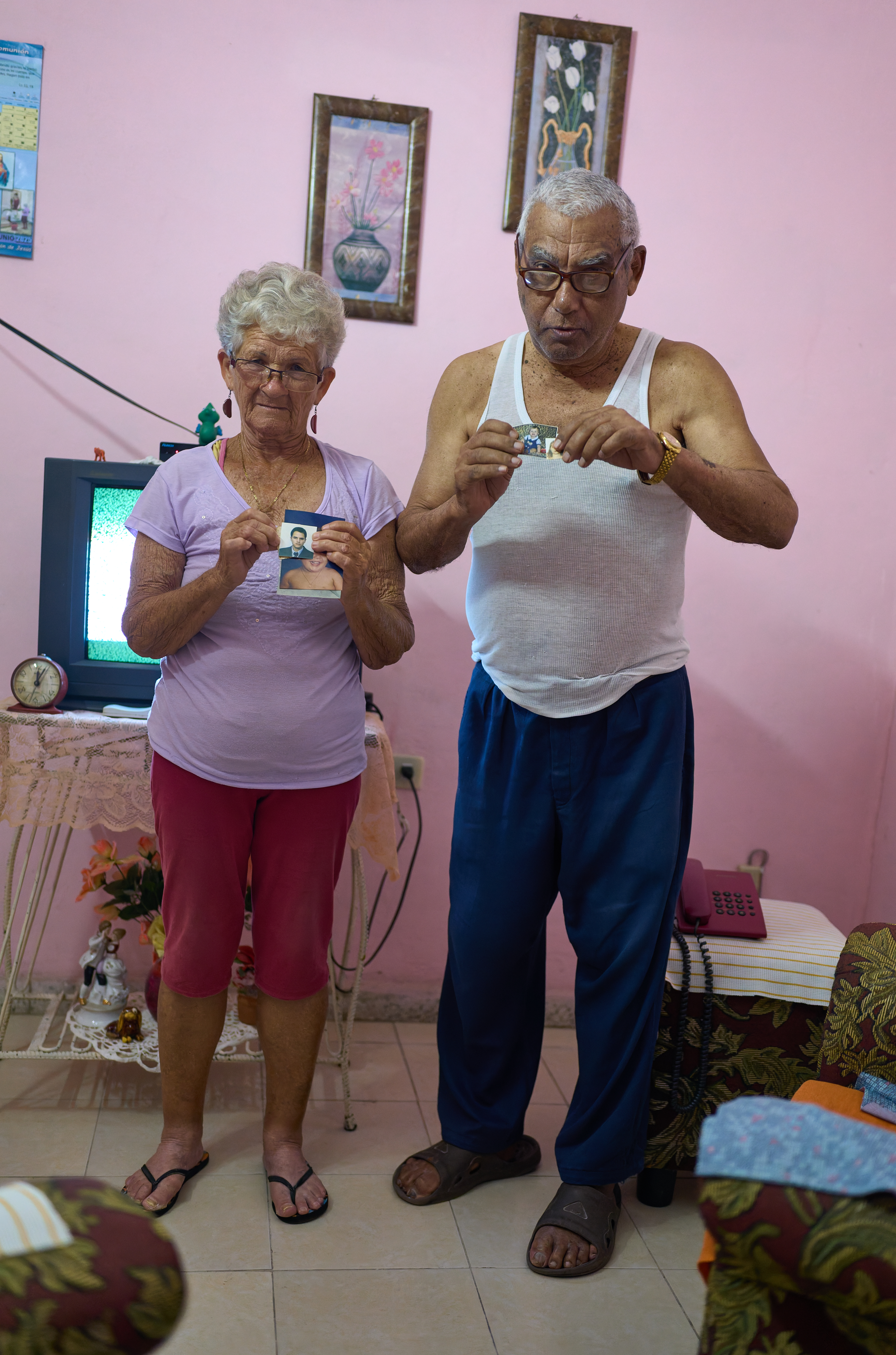 Photos of a Distant Family:  The couple holds a photograph of their children, whom they haven’t seen in over five years. Distance and economic hardship have made visits impossible.