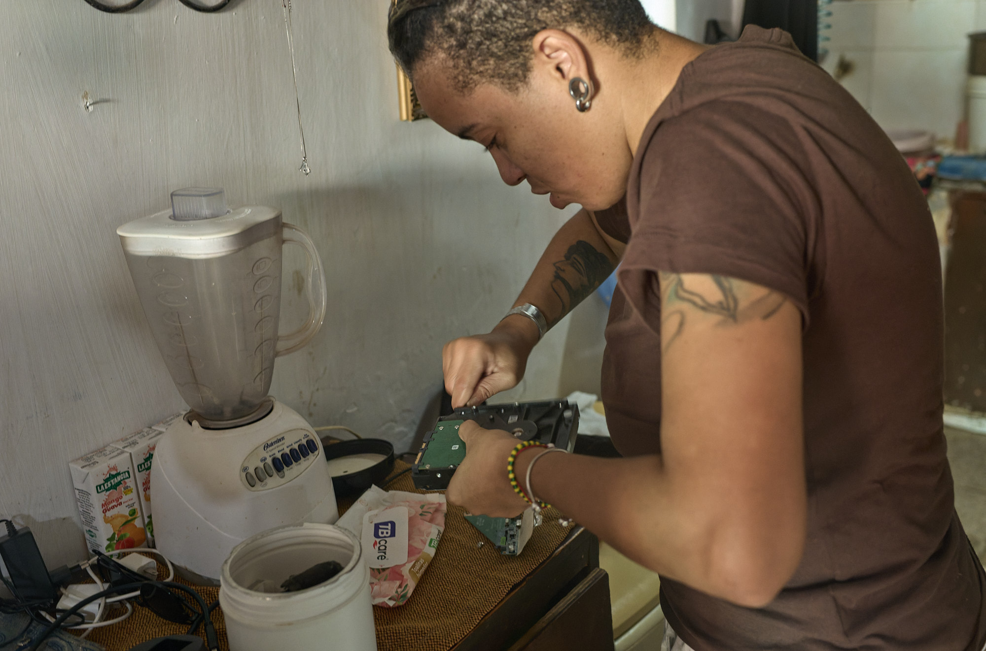 Yordanka attempts to fix a dead hard drive holding their old business images. It’s not nostalgia — it’s survival. These lost photos are their shot at new clients and income.