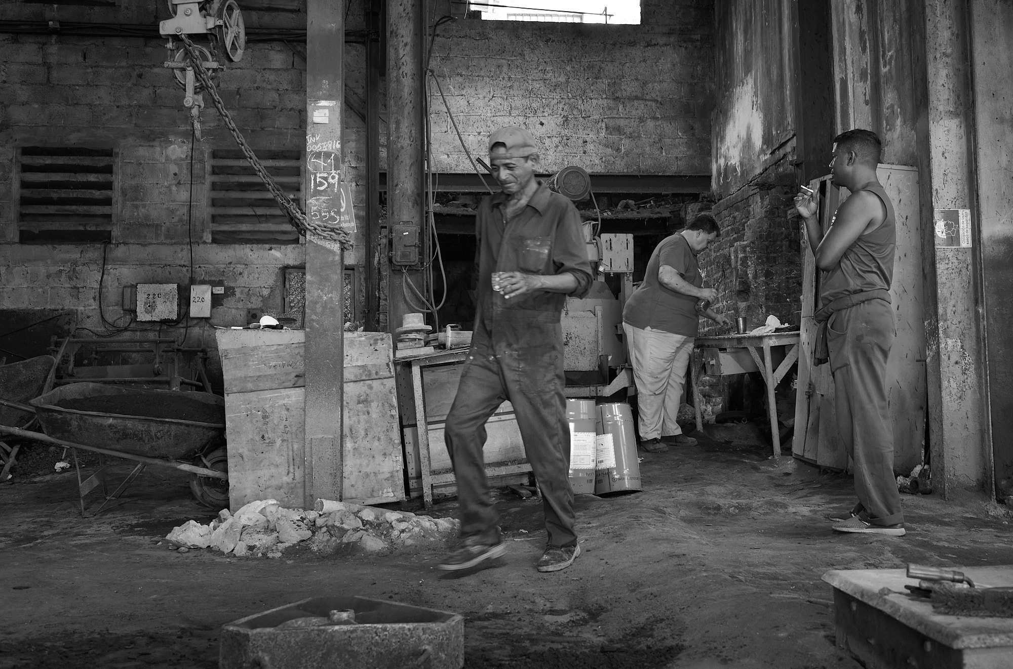 Denis walks back to work, vodka in hand. The moment passes without comment — a glimpse into the rhythms that carry men through long hours in a space where rules bend and coping becomes habit.
