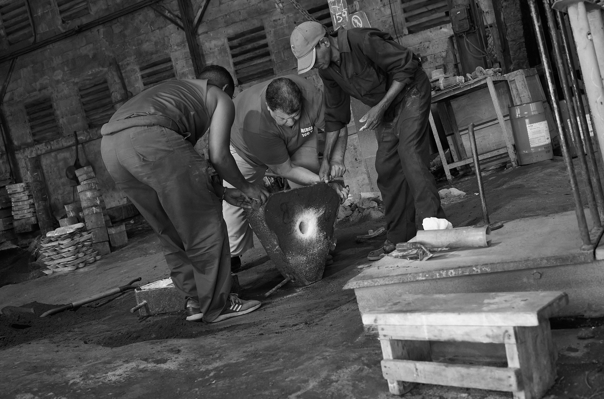 It takes all three to flip the heavy casting mold — a coordinated effort born from routine, not rehearsal. There’s no equipment to help. Just hands, weight, and the quiet expectation that the job gets done.