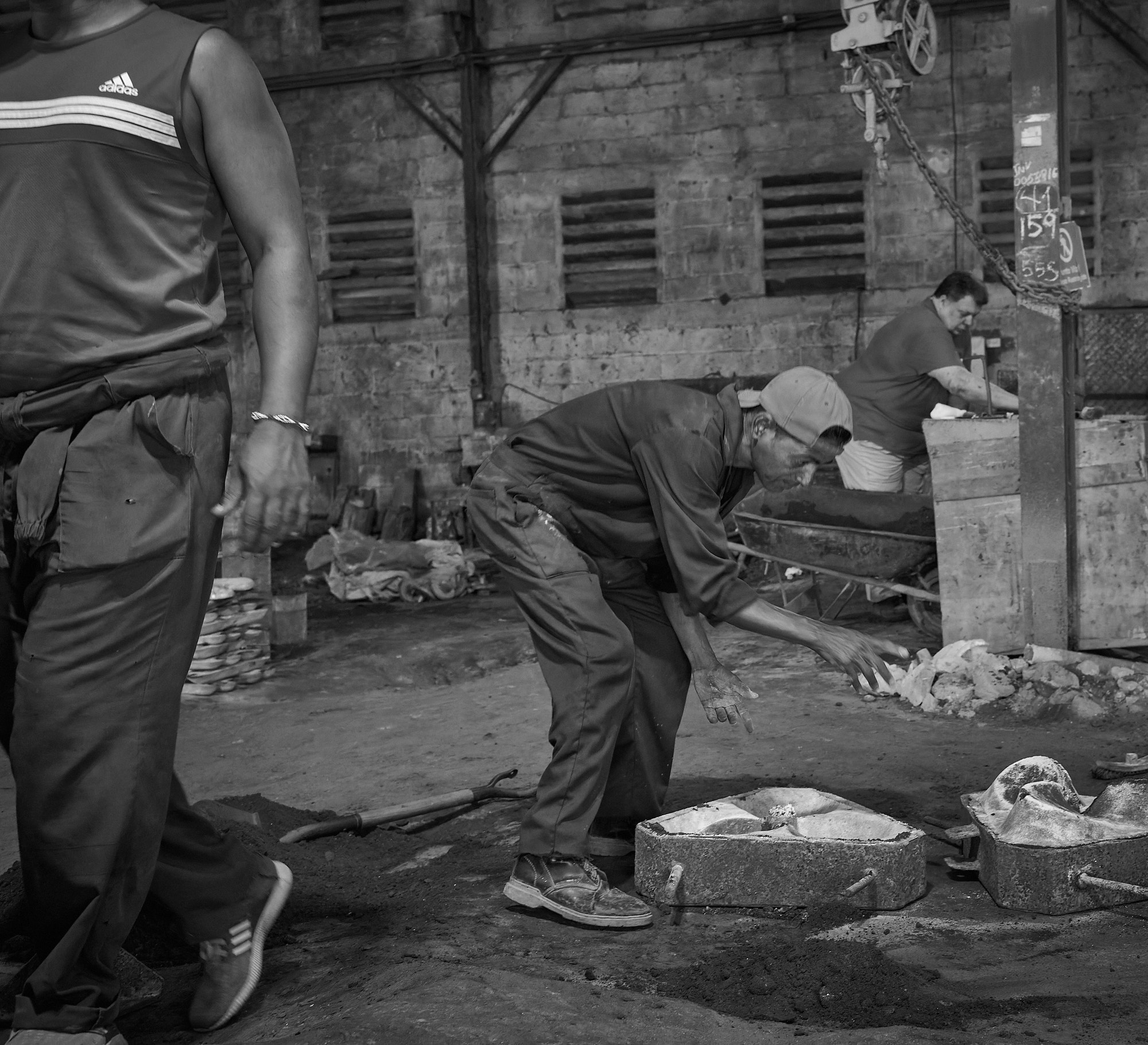 The casting process unfolds exactly as it has for decades. Denis crouches over his work, focused and unprotected, in a space thick with fumes and routine. Safety isn’t missing — it was never expected.