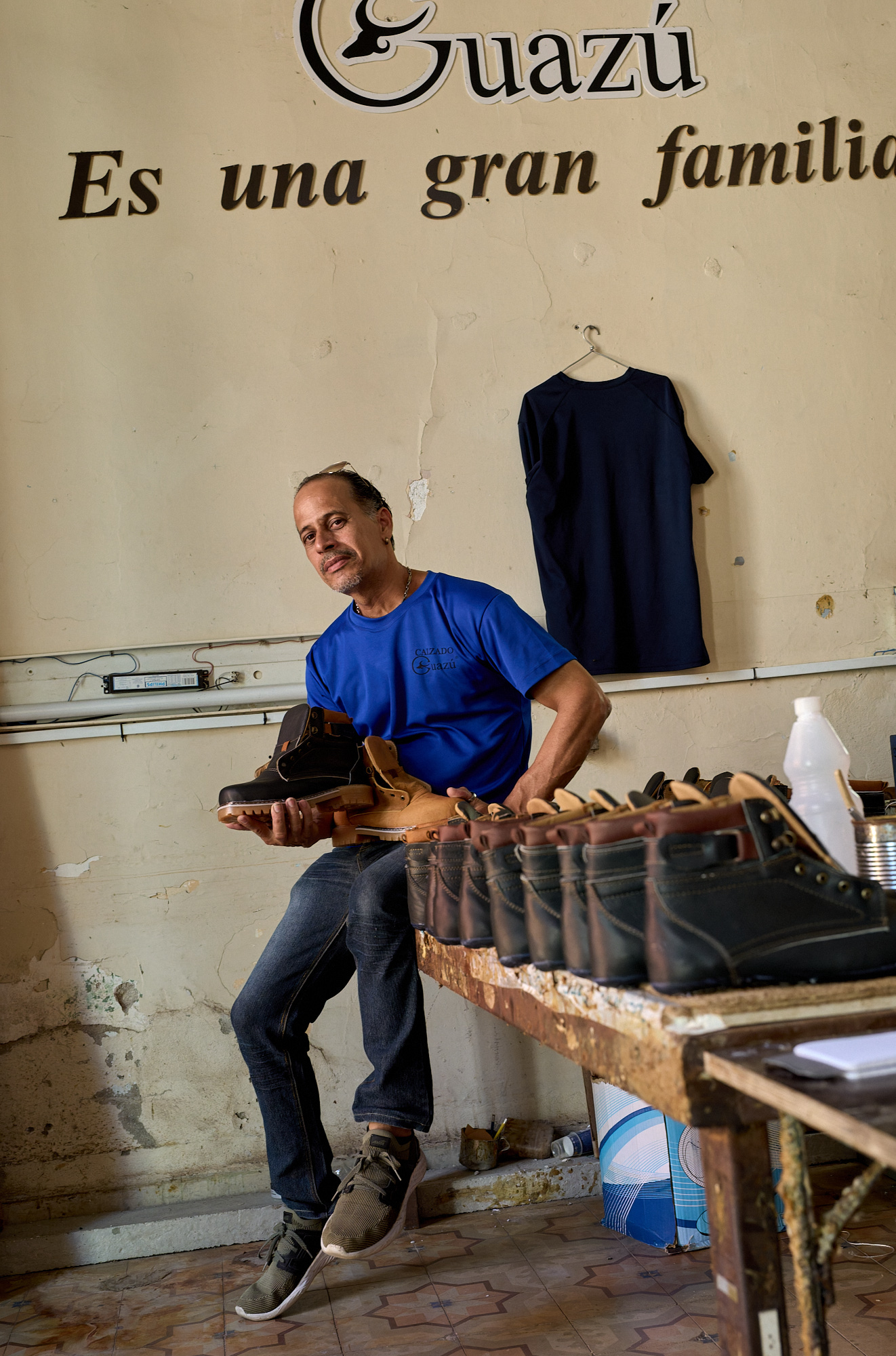 The worker featured in the image is one of two designers responsible for creating shoe designs at the workshop. His role reflects both creative and technical expertise within a small private enterprise operating under material constraints and limited resources.