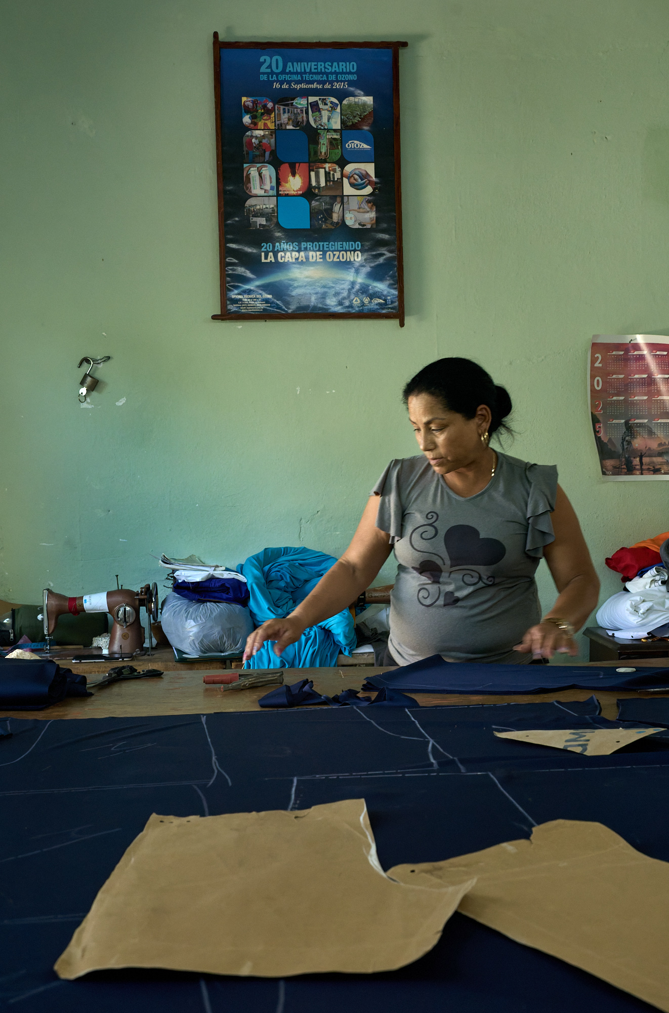In her Havana workshop, Naomi traces a clothing pattern across deep-blue fabric. Once a state employee, she now owns the shop herself, cutting new designs in a space once defined by bureaucracy.