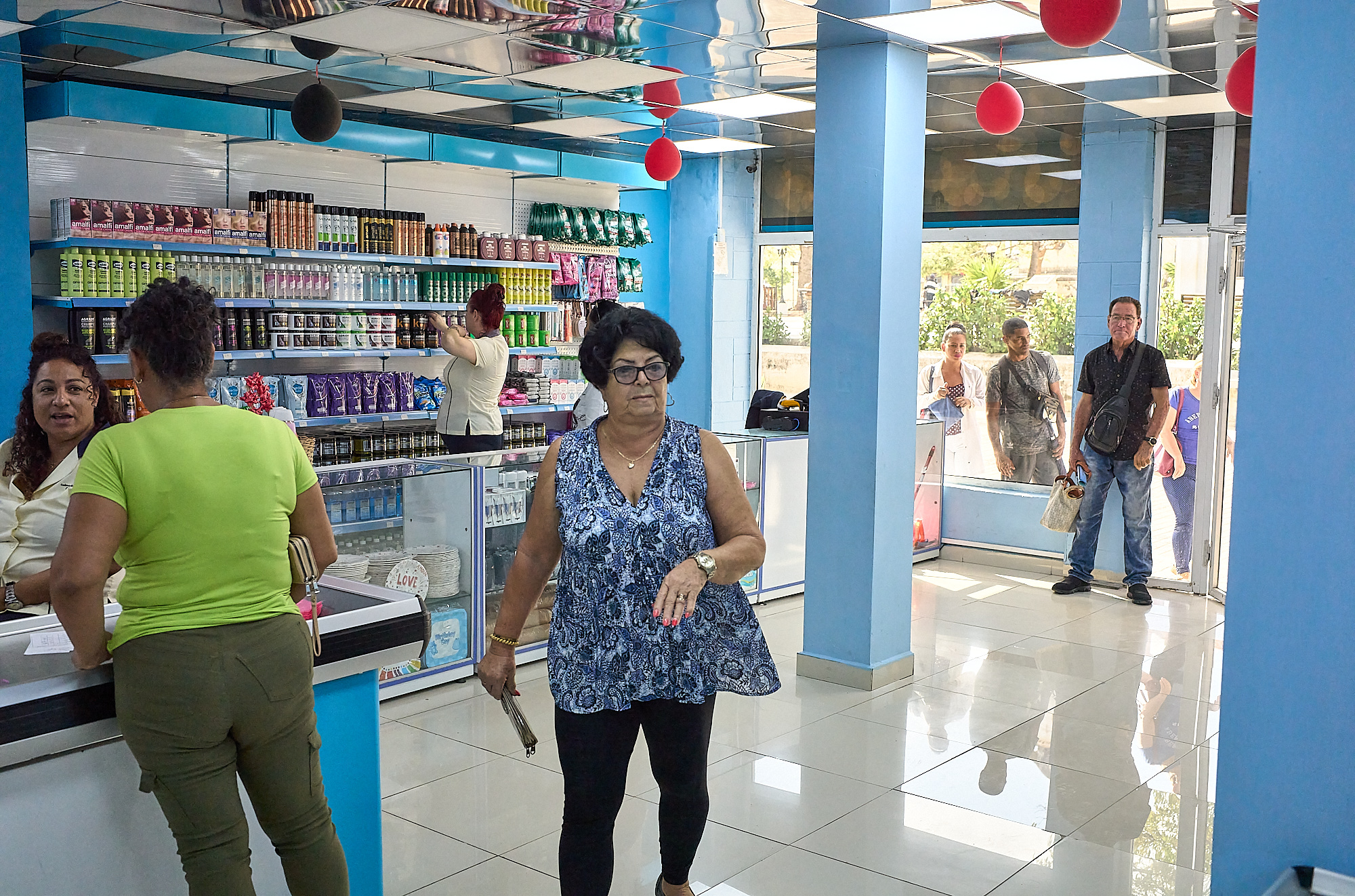 Fluorescent light bounces off mirrored ceilings and glossy tile inside Casa Grande, one of Havana’s dollar-only MLC store. Shelves gleam with imported brands, a rare abundance in Cuba. Outside, onlookers peer through the glass, separated not by distance, but by currency.