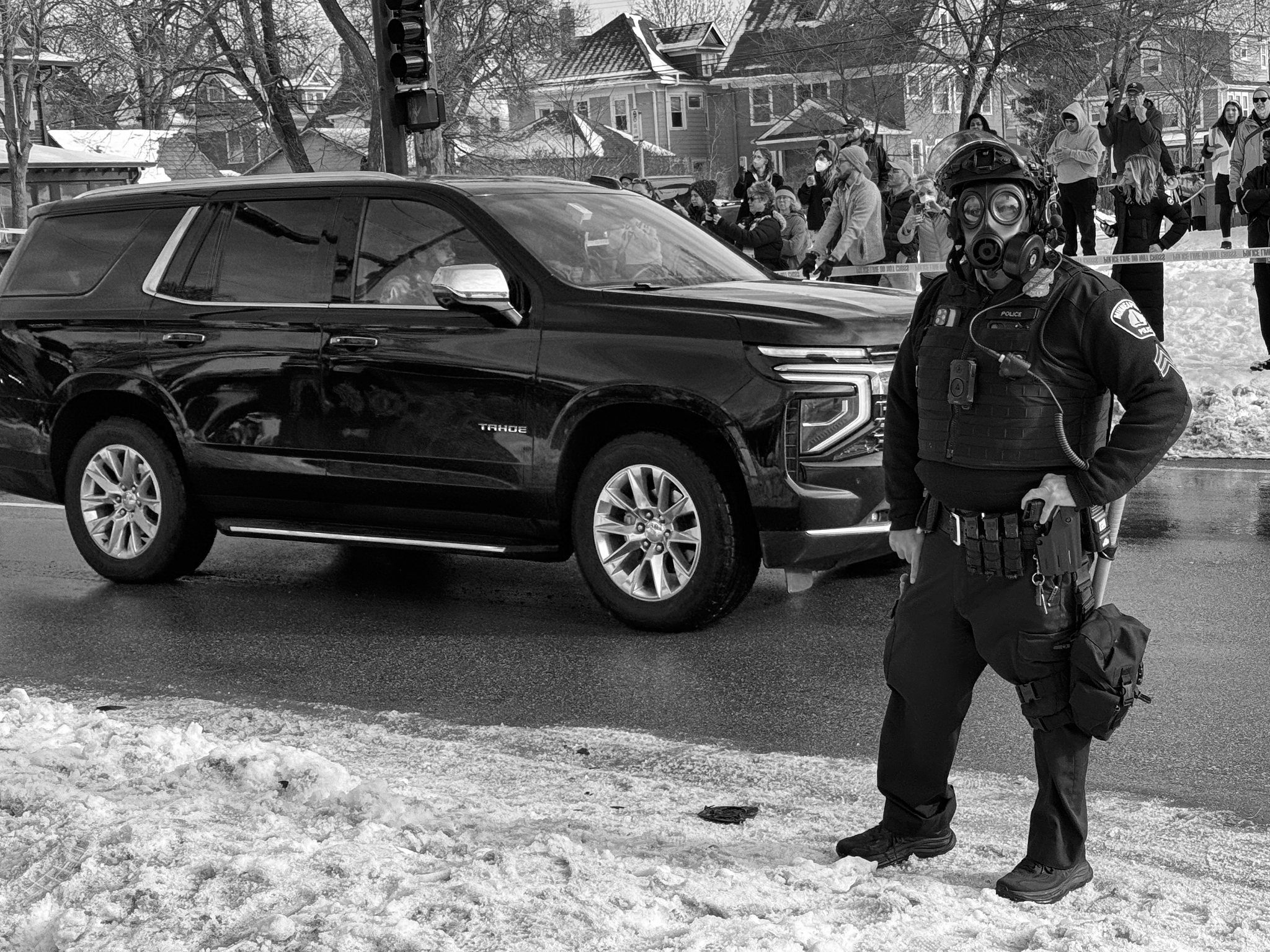 Minneapolis police provide security as an ICE vehicle leaves a residential intersection following a fatal enforcement action. Chemical agents had been deployed earlier in response to crowd activity.