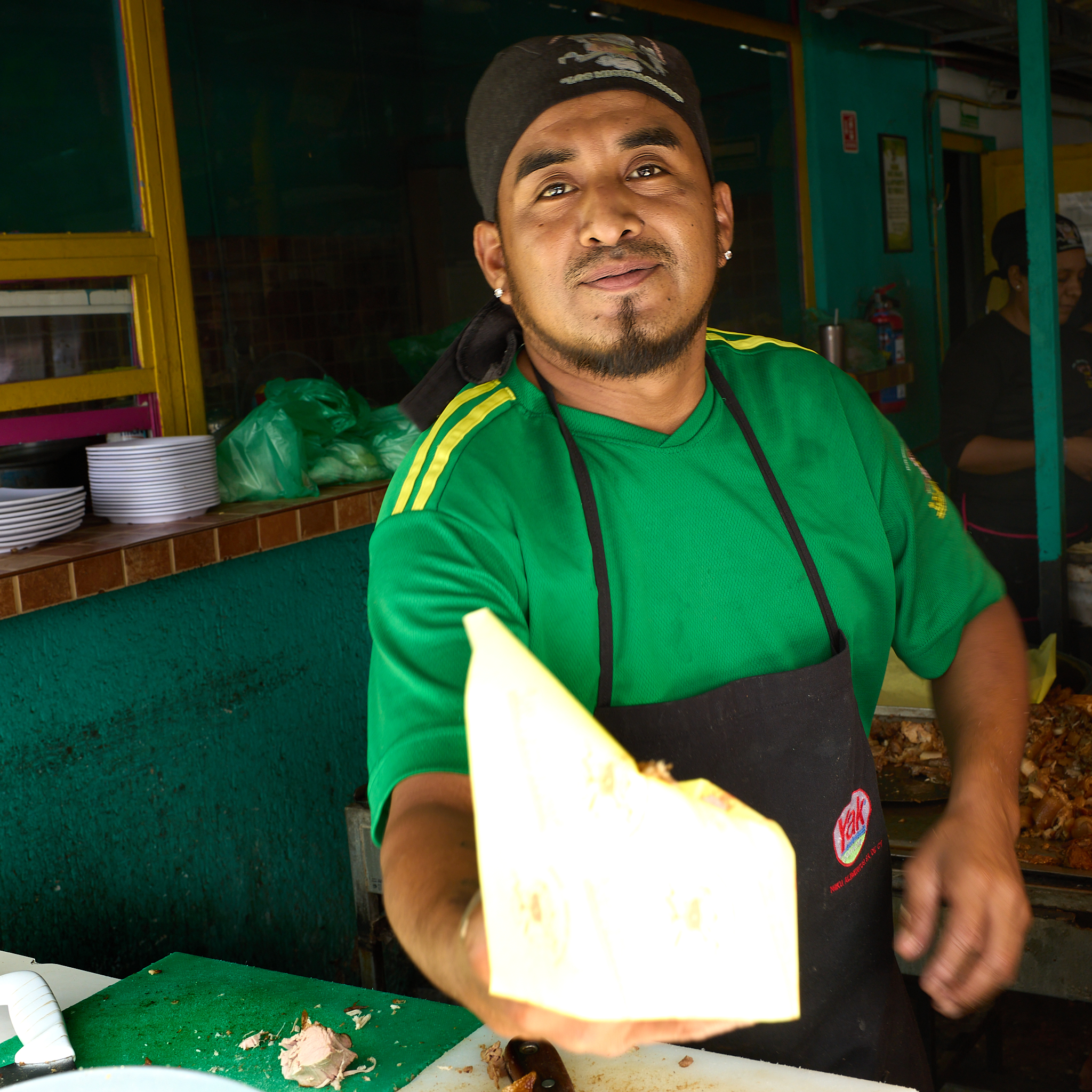 Inside Carnitas los Michoacanos, where food is cooked fresh in front of customers. Orders are taken by ticket, and the cook serves each plate directly during the busy lunch rush.