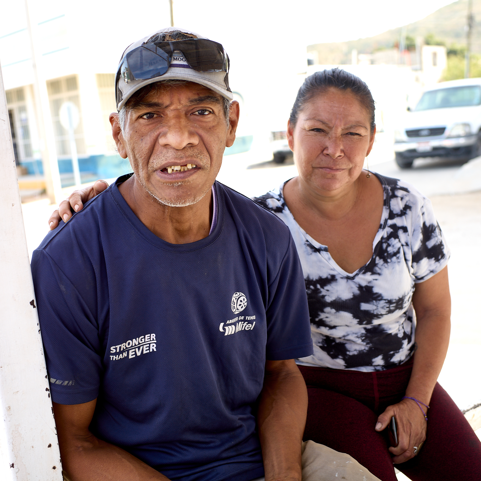 A man and his wife wait at a bus stop in Cabo San Lucas. Deported from the United States five years ago, he says he feels freer here because he no longer lives under the threat of detention or deportation, despite having less materially.