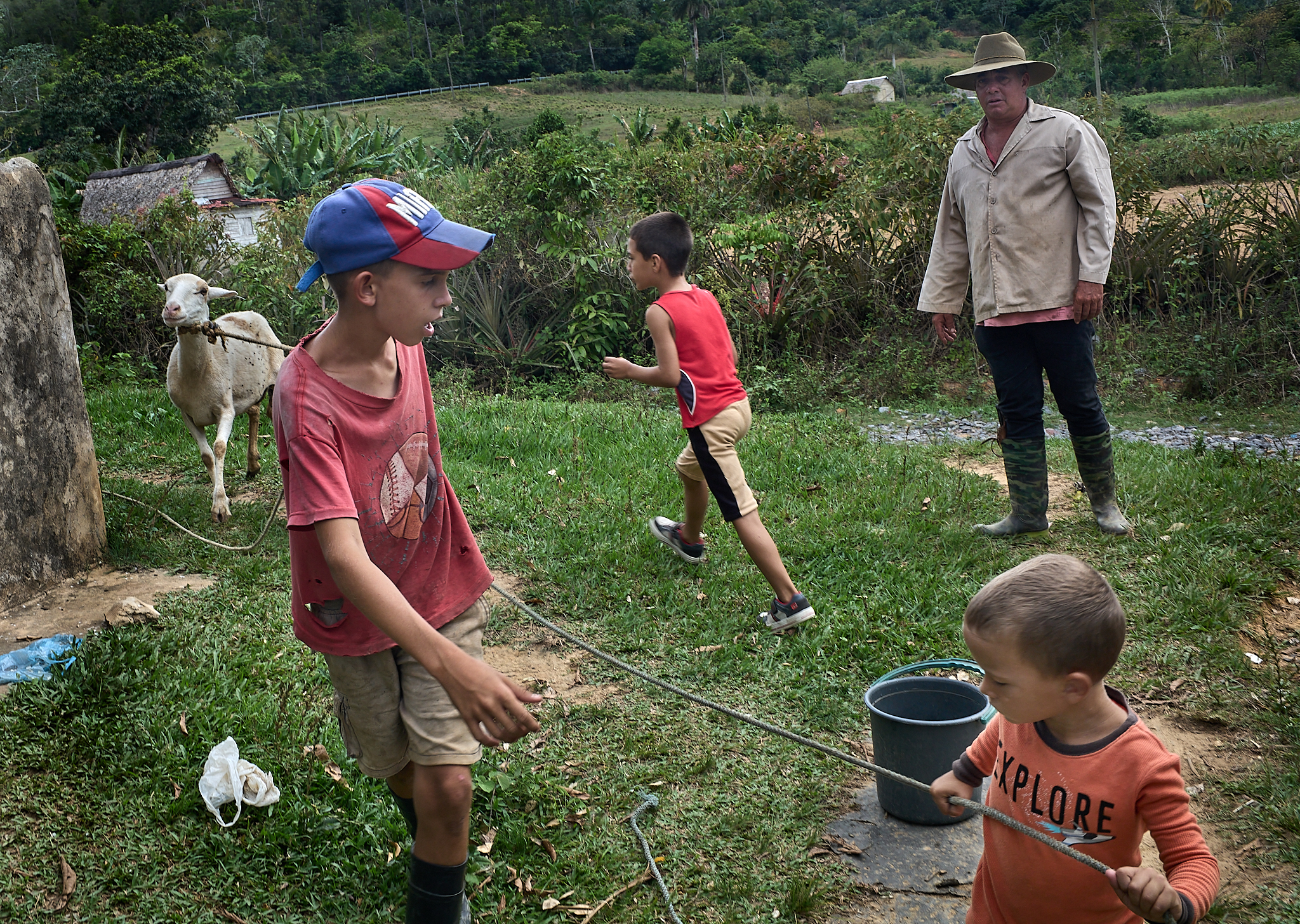 Michel stands nearby as his sons and a neighbor’s child run and play in the front yard of their rural home—one corner of a multigenerational tobacco farm that’s been in the family for five generations.