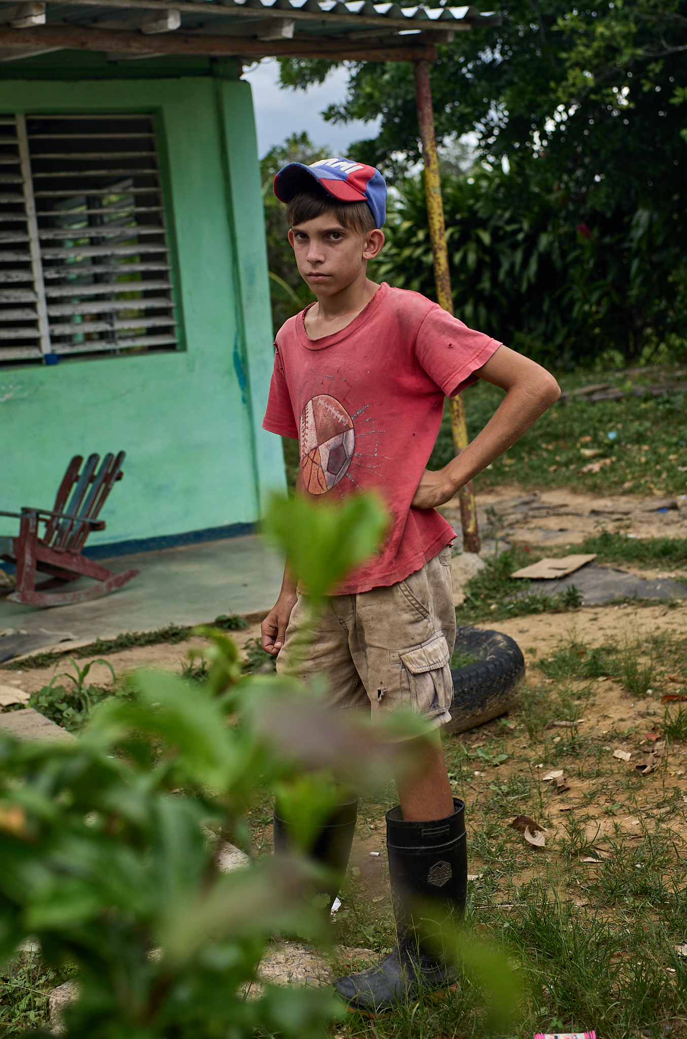 A boy from a nearby home stands outside during a rainy pause in the tobacco season.